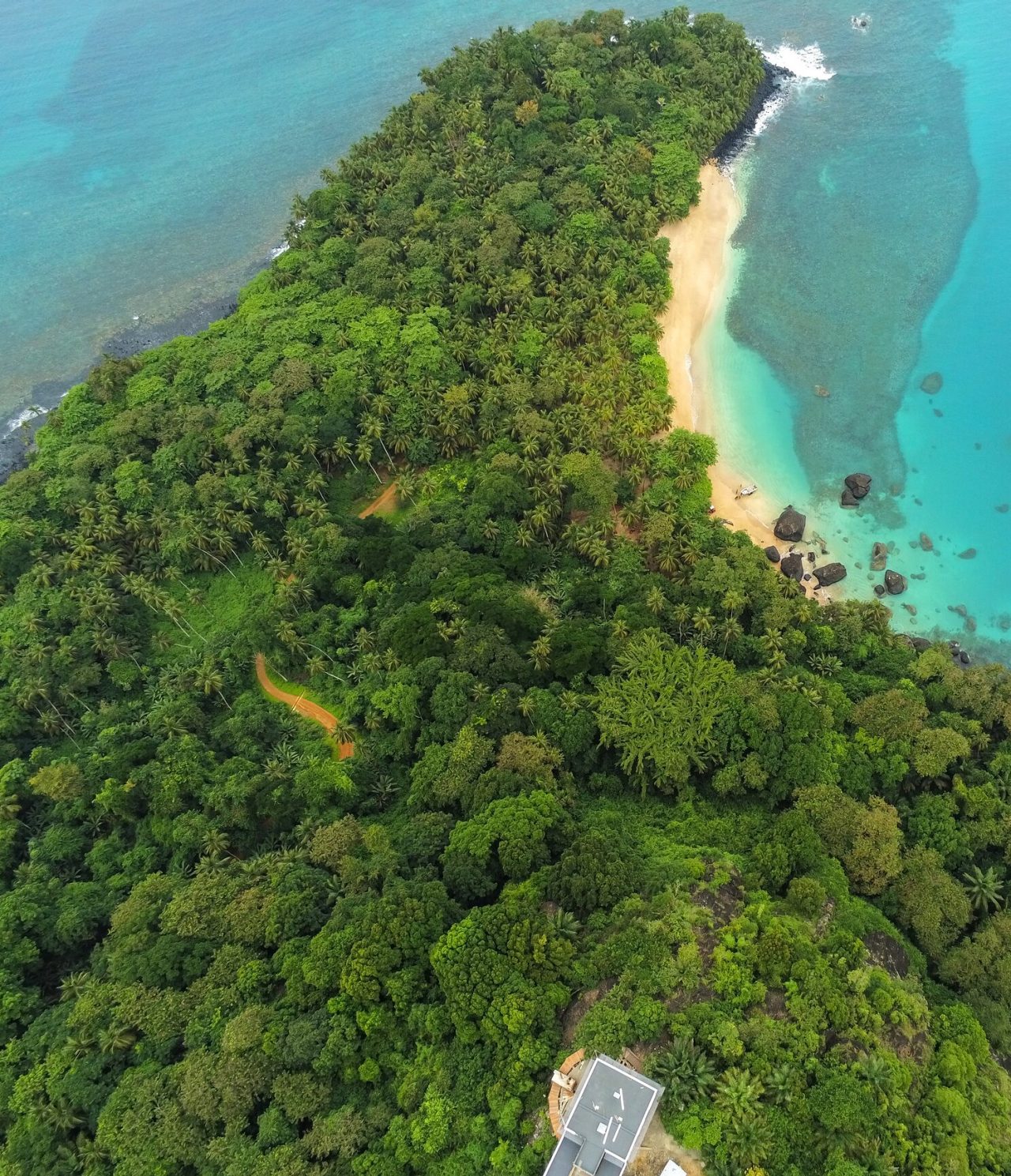 Luchtzicht op het eiland São Tomé en Príncipe, met weelderige vegetatie, een wit zandstrand en kristalhelder water