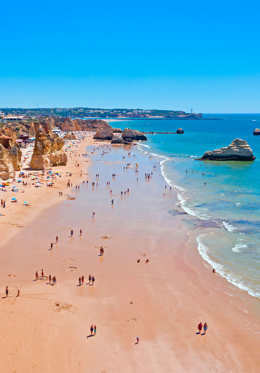 Luchtfoto van Praia da Rocha met parasols, kliffen, mensen, rotsen en de zee, onder een heldere lucht