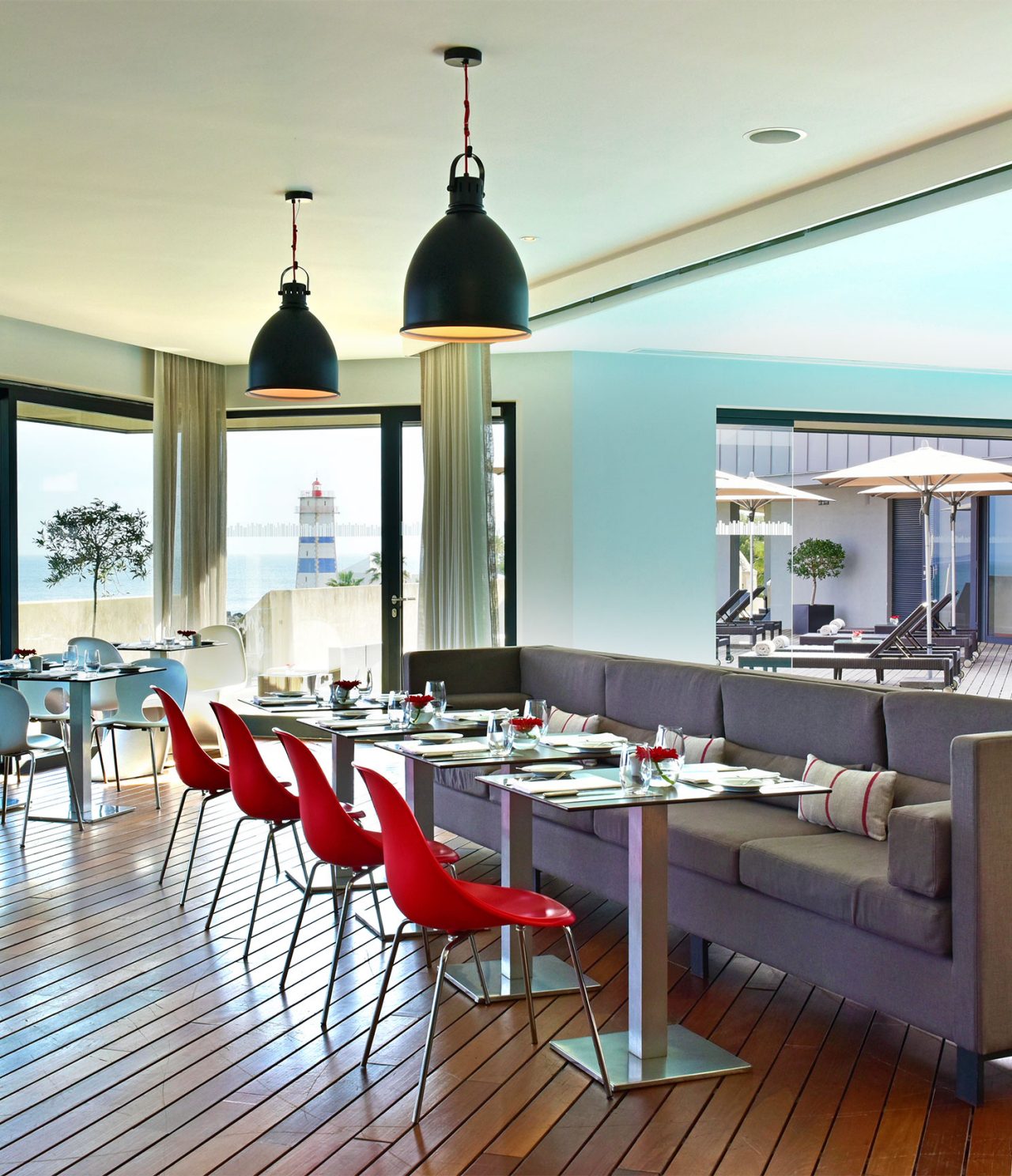 Het restaurant Maris Stella, van het 5-sterrenhotel in Cascais, heeft een grijze bank met rode tafels en stoelen