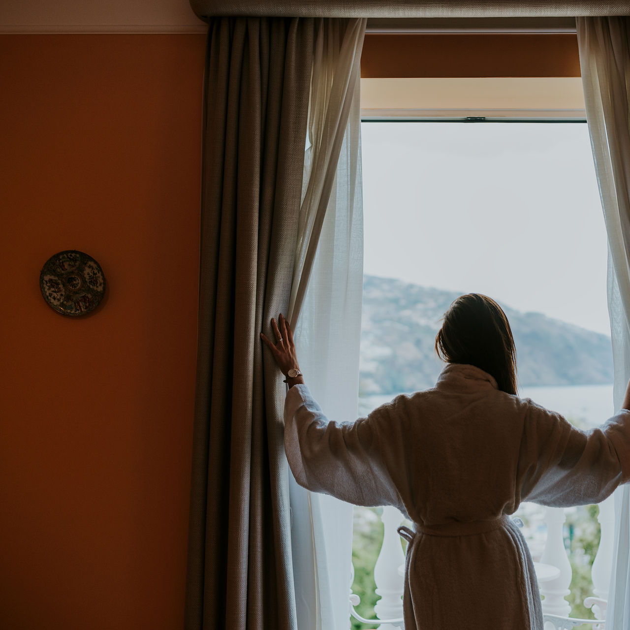 Vrouw in badjas geniet van zeezicht vanuit hotel in Madeira, nabij strand met zwembad