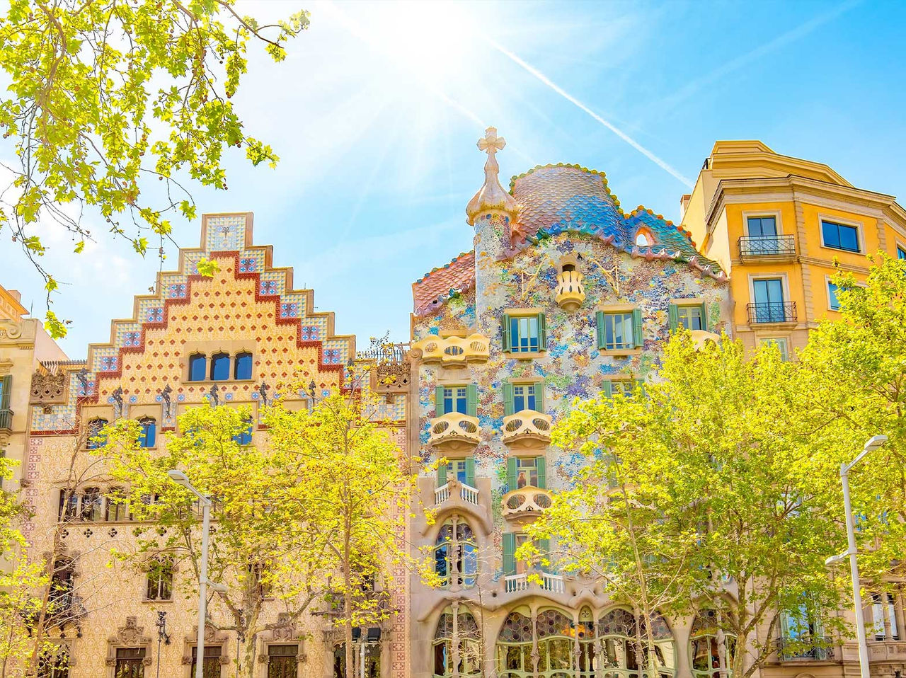 Iconisch Casa Batlló gebouw van Gaudí in Barcelona, met zijn kleurrijke gevel, omgeven door bloeiende bomen