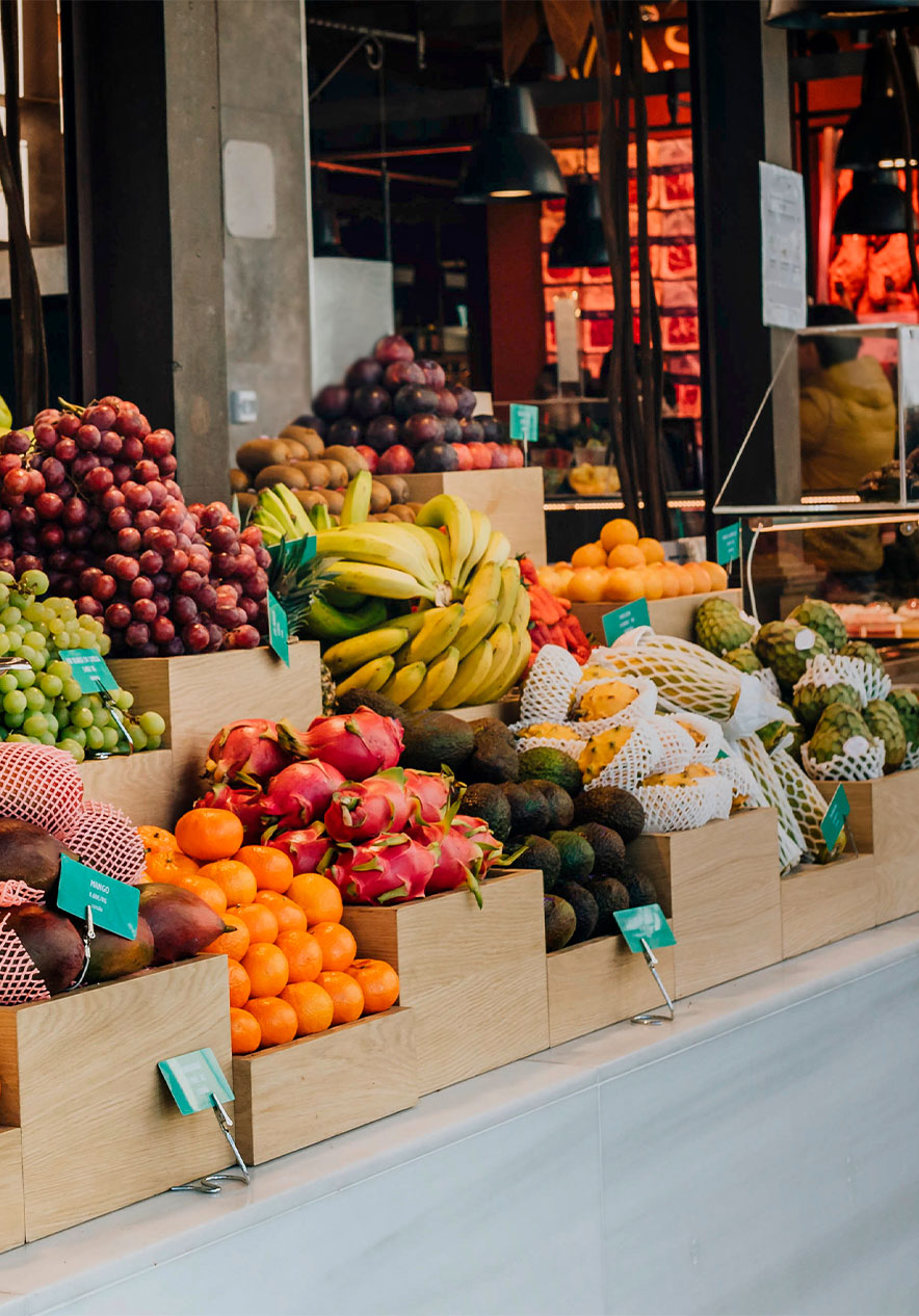 Kraam met diverse vruchten op de Mercado de San Miguel, met een weegschaal en zwarte hanglampen boven