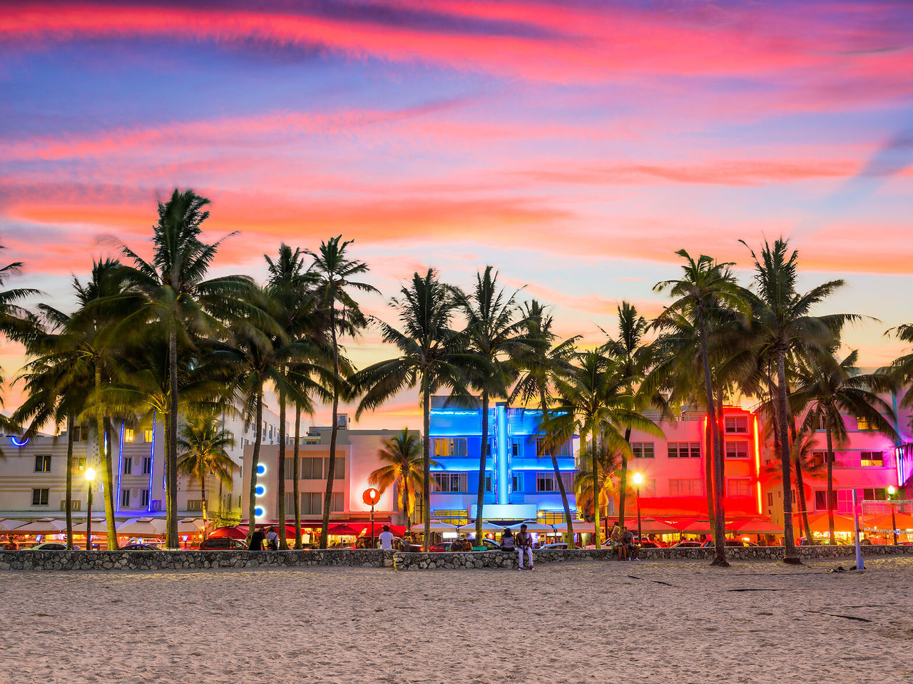 Levendige zonsondergang in Miami Beach, met silhouet palmbomen en verlichte Art Deco-gebouwen