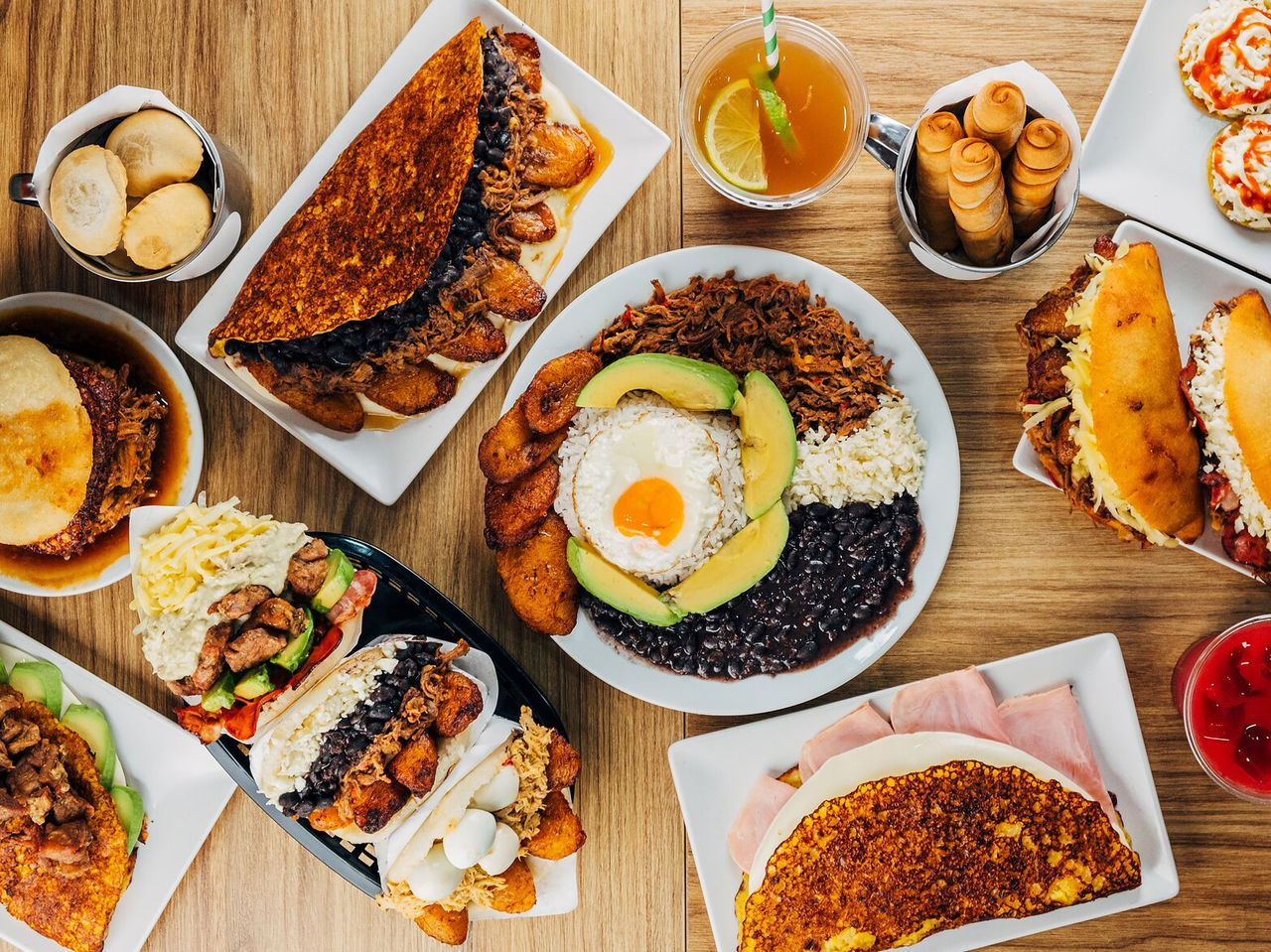 Tafel vol typische Venezolaanse gerechten, waaronder arepas, tequeños en chapachas