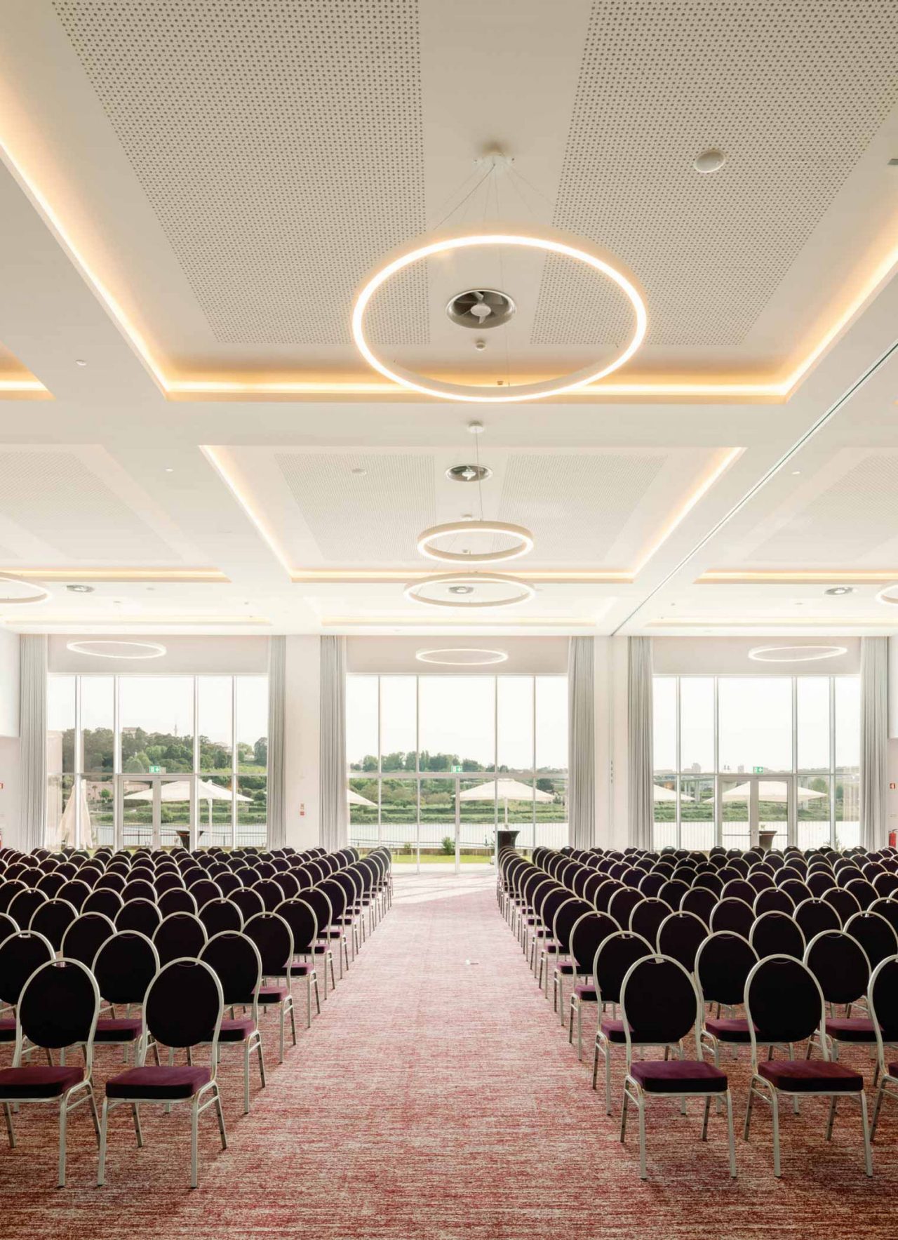 Ruimte voor vergaderingen of conferenties, in een ruime zaal met meerdere stoelen en ramen die natuurlijk licht toelaten
