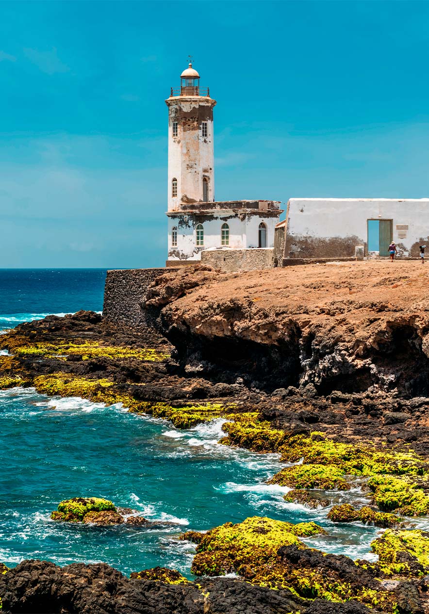 Coastal lighthouse in Cape Verde over rocky cliffs with the blue sea in the background