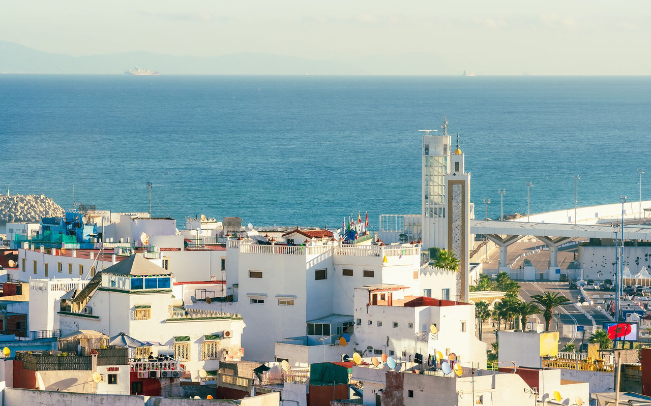 Vista da cidade de Tânger, Marrocos, com edifícios brancos de arquitetura tradicional marroquina e mar azul ao fundo