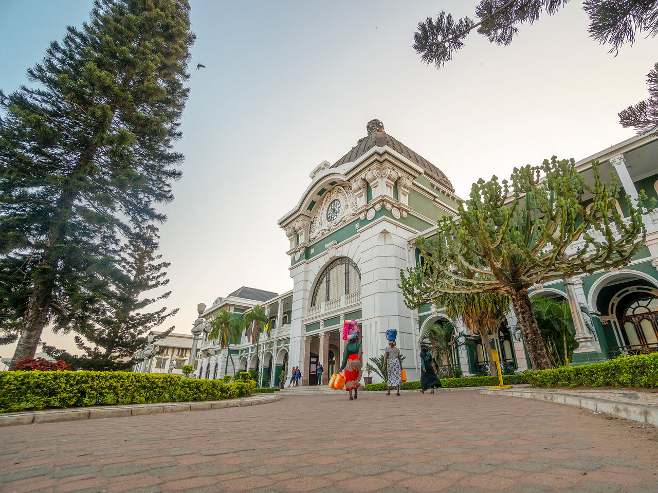 Colonial building in Maputo in green tones, with three Mozambican women carrying their belongings on their heads