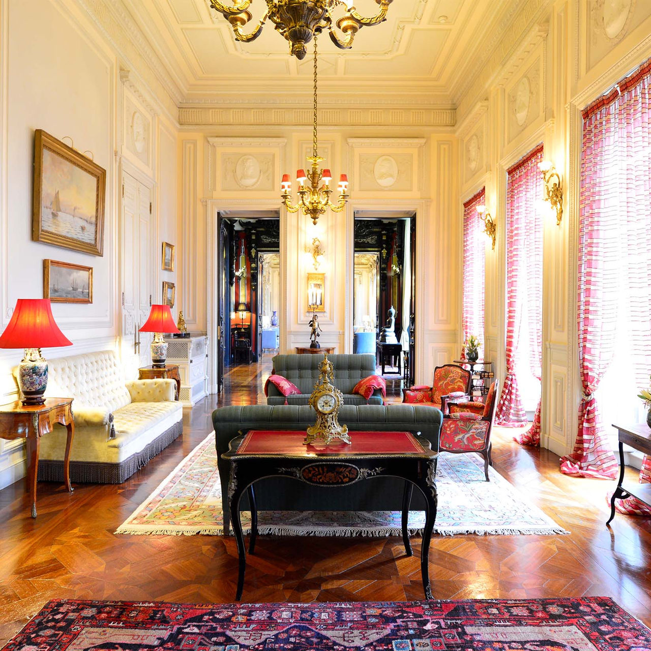 Room at Pestana Palace Lisboa, with upholstered sofas and armchairs, two golden chandeliers, and wood-paneled walls