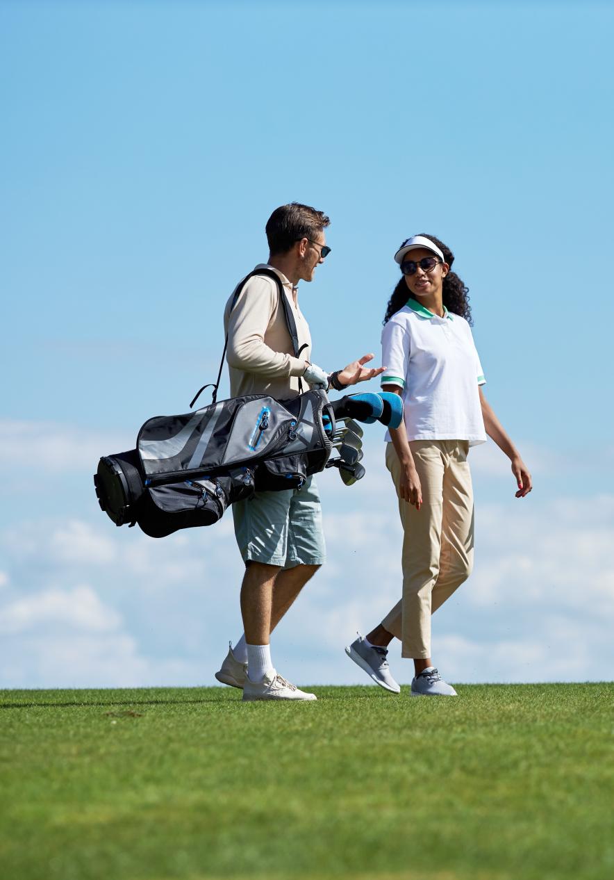 Couple carrying golf clubs on a golf course in Porto Santo with a blue sky