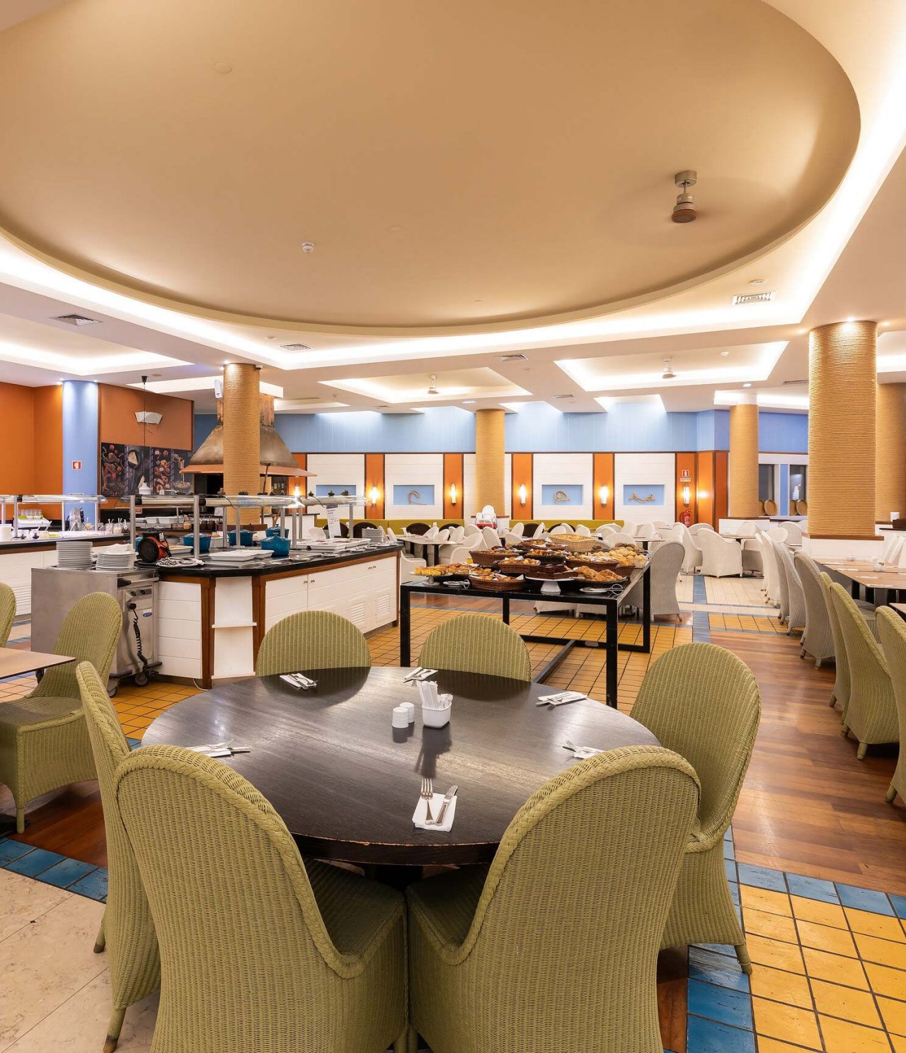 The Marés restaurant at the 5-star Resort in Porto Santo has a spacious area with yellow walls and green chairs.